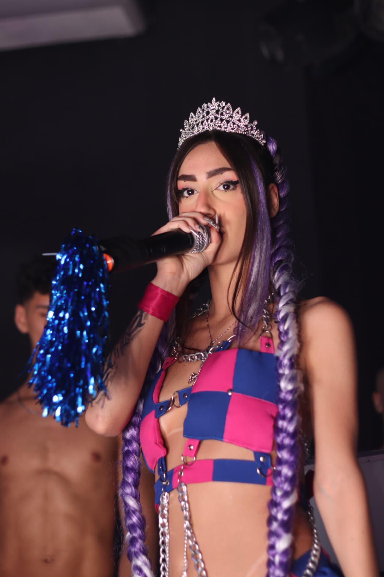 Cantora com tiara brilhante e microfone se apresentando no palco